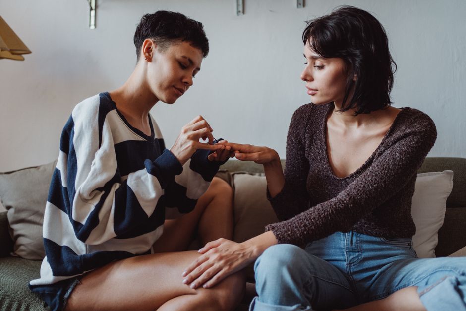 Two women enjoying a relaxed moment painting nails on a sofa