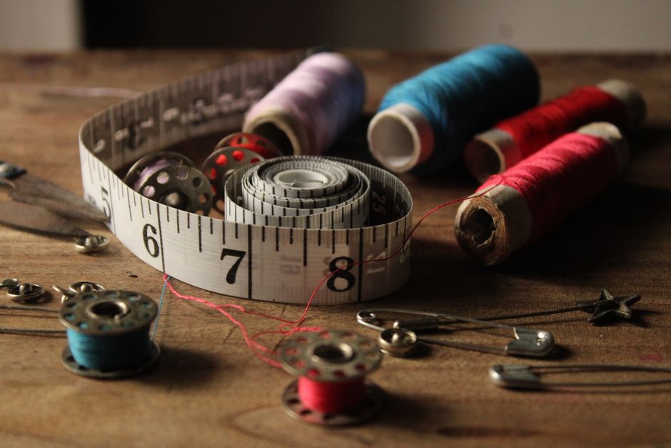 A collection of vibrant sewing materials including threads, bobbins, and a measuring tape on a wooden background