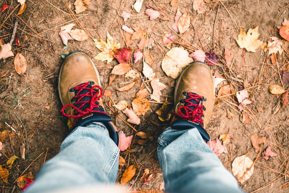 Pair of boots stepping on dry autumn leaves