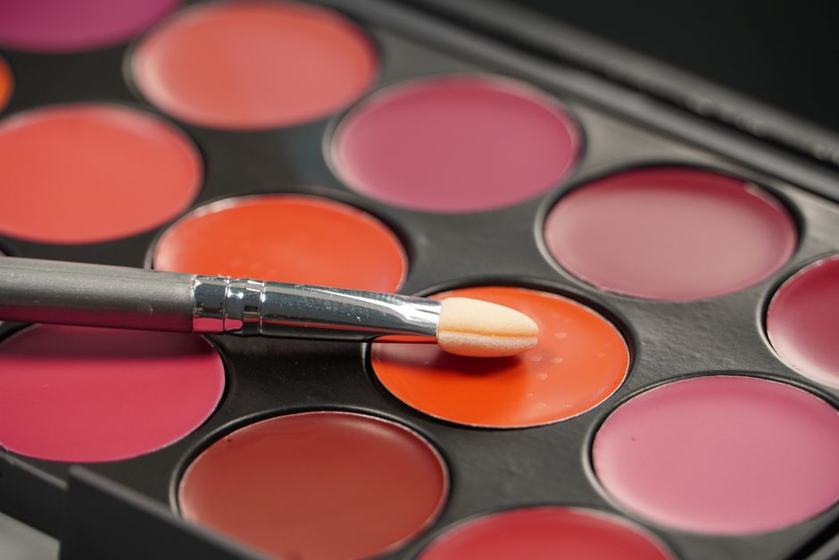 Close-up of colorful makeup palette with a brush resting on a vibrant red shade