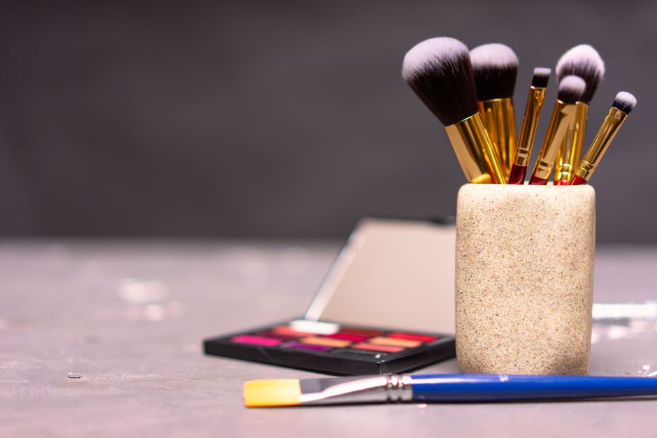 A stylish display of makeup brushes in a holder alongside a colorful palette