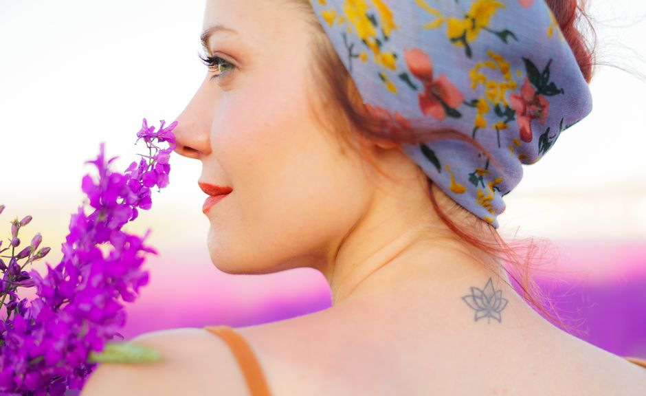 A woman in a floral headscarf enjoying lavender in a sunny field