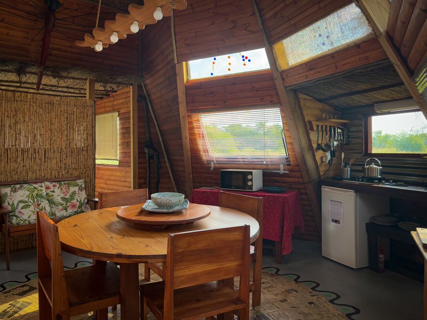 A cozy wooden cabin interior featuring a dining area, kitchenette, and rustic decor