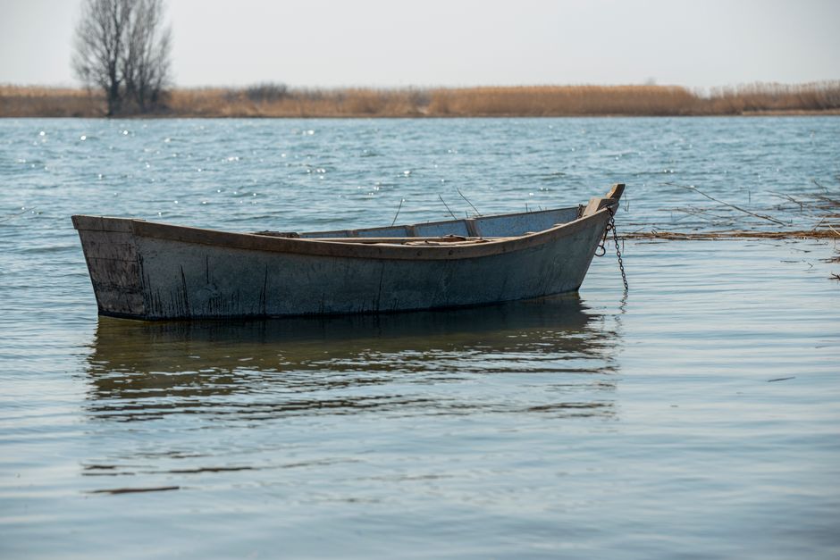 A lone wooden boat peacefully floats on a calm lake under a clear sky