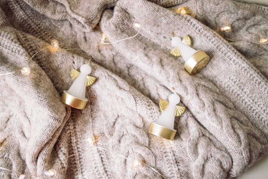 Charming holiday scene with angel ornaments and fairy lights on a knitted sweater