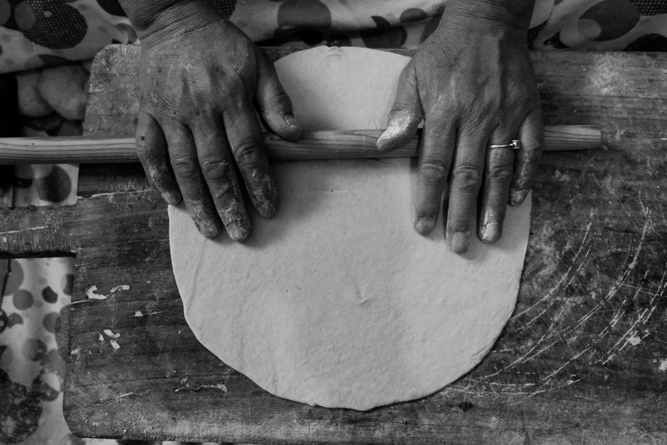 Hands rolling dough on a rustic wooden surface