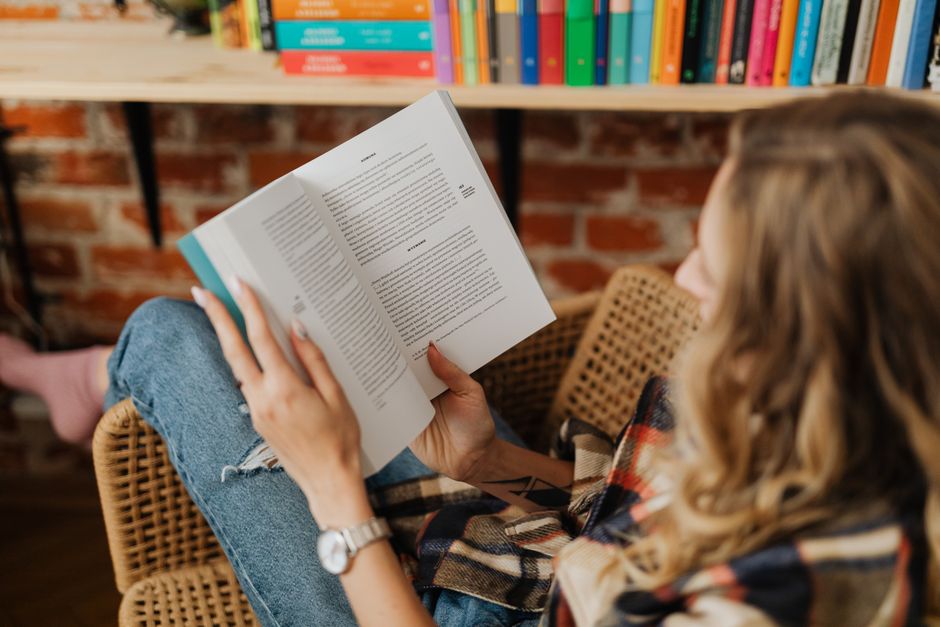 A woman sitting comfortably indoors enjoying her book in a cozy and peaceful setting