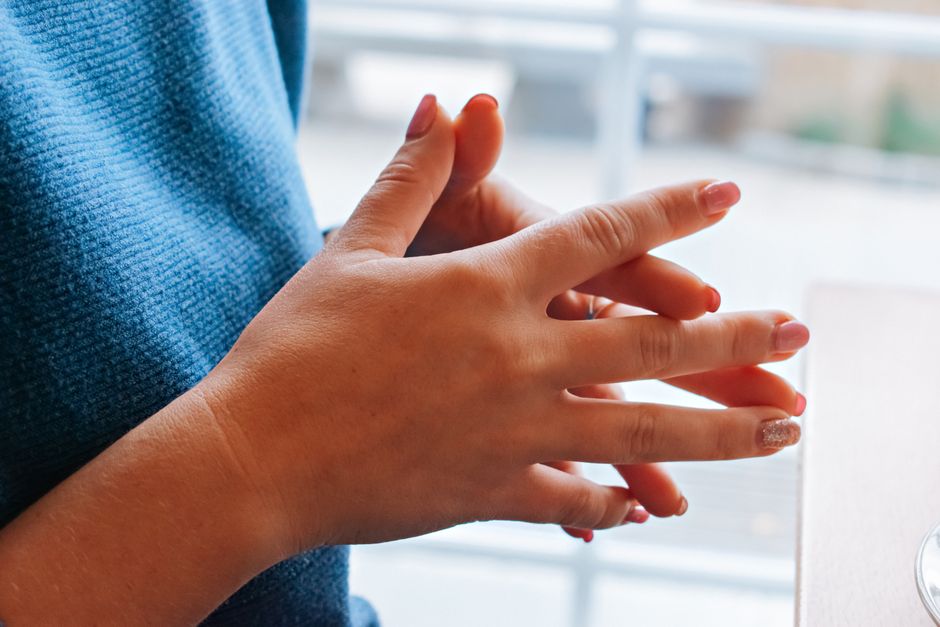 Close-up of elegantly manicured hands with glittery nail polish resting casually on a table