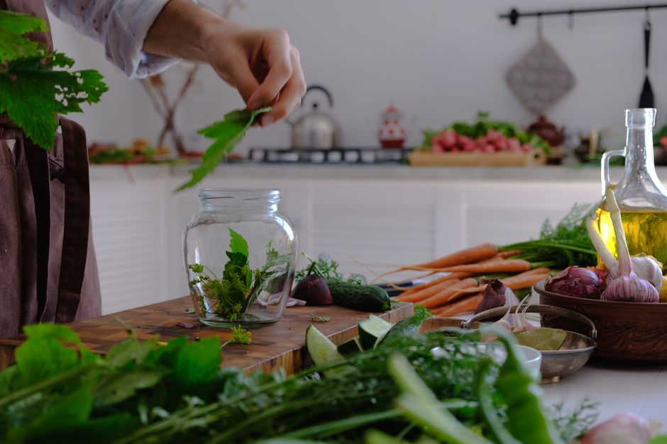 Hand preparing herbs and vegetables in a kitchen setting