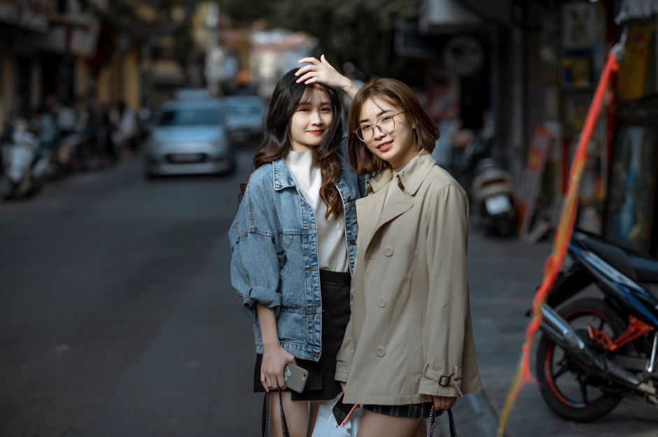 Two young women walking together along a busy street
