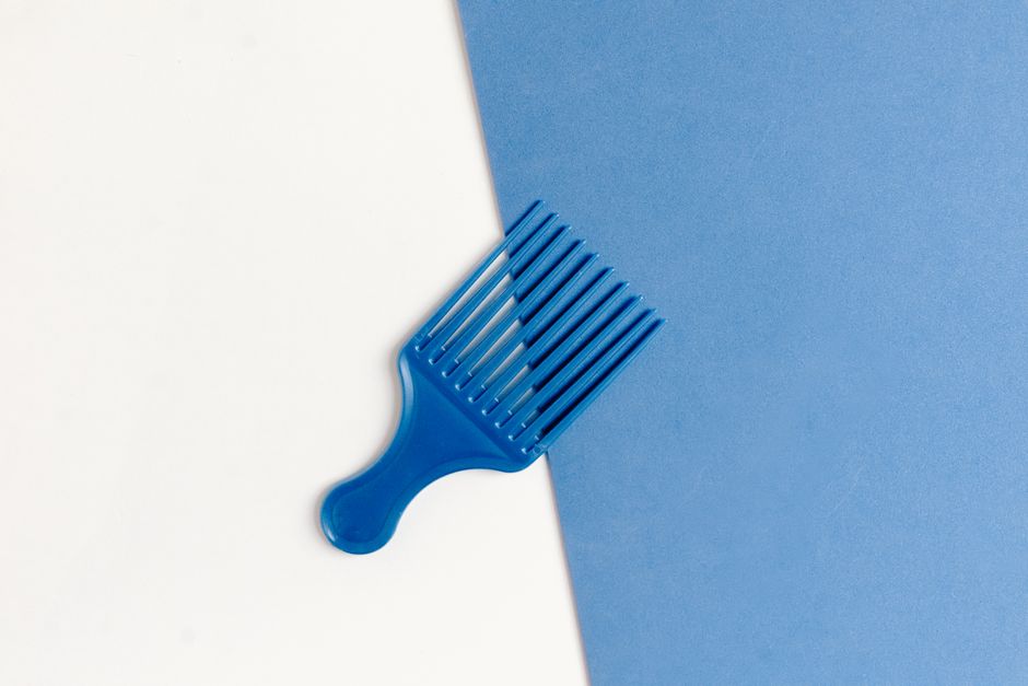 Stylish blue plastic comb on a dual-tone white and blue background