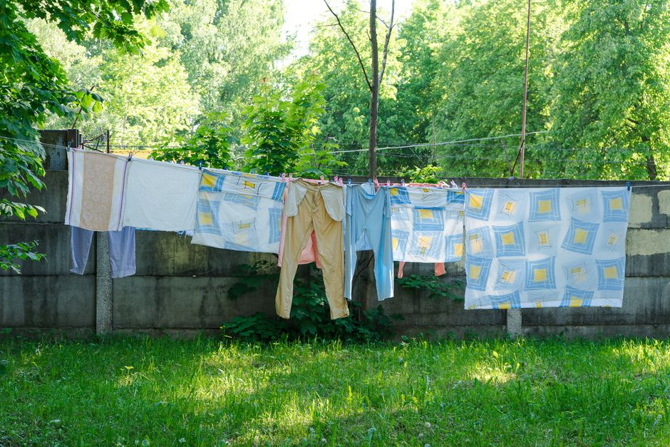Vibrant clothes and sheets drying on a line outside surrounded by lush greenery