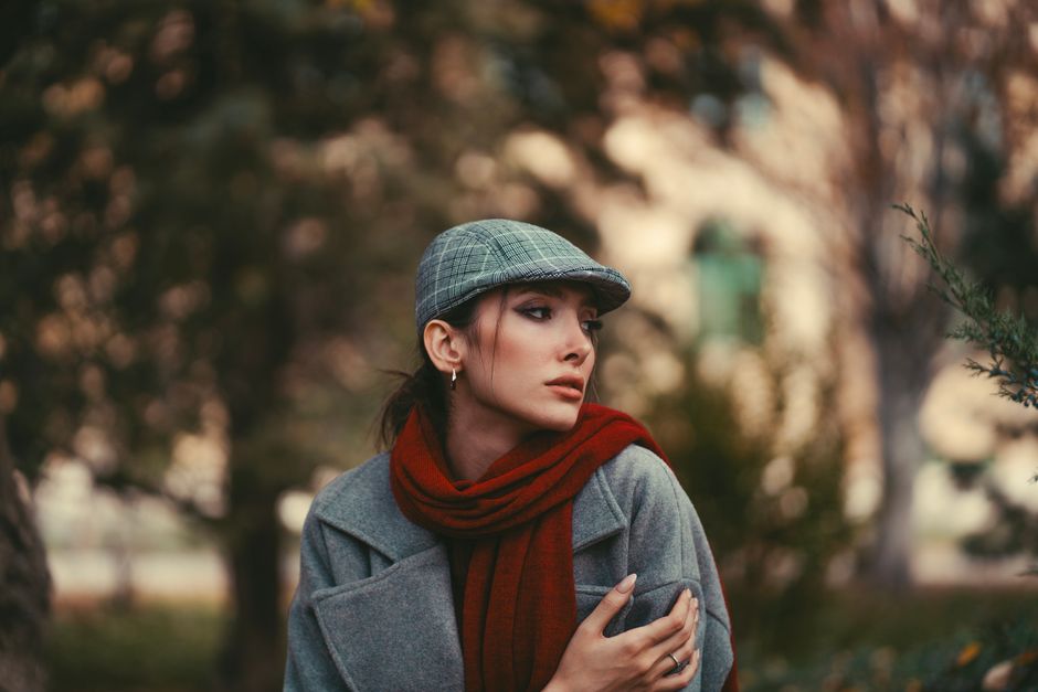 Stylish woman wearing a vintage cap and red scarf outdoors